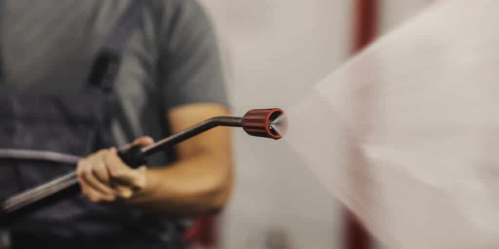 Close up of a nozzle and water gun jet at car wash station.